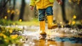 Feet of child in yellow rubber boots jumping over a puddle in the rain. Royalty Free Stock Photo