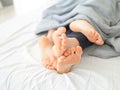 Feet of couple sleeping side by side in comfortable bed. Close up of feet in a bed under white blanket. Bare feet of a Royalty Free Stock Photo