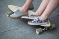 Feet couple of teenagers in sneakers on longboard