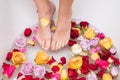 Woman Feet dipped into a spa and aromatherapy bowl with rose petals and heads. Close-up photo in bathroom. Beauty treatment Royalty Free Stock Photo