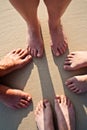 Feet of a family in the fine sand of the beach