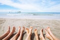 Feet of family or group of friends on the beach, many people sitting together