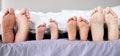 Feet of family lying in bed. Closeup of feet of parents and children in bed. Family relaxing in bed together. Below bare Royalty Free Stock Photo