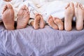 Feet of family lying in bed. Closeup of feet of parents and children in bed. Family relaxing in bed together. Below bare Royalty Free Stock Photo