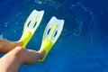 Feet with flippers on the blue sea while snorkeling.