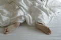 The feet or foot of couples sleeping on the bed and cover by the white blanket on a bright Sunday morning Royalty Free Stock Photo