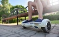 Feet of a girl child on a hoverboard while relaxing on a bench in a park Royalty Free Stock Photo