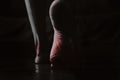 The feet of a girl on the floor of the house are highlighted in red in the dark, black and white photo, pain in the Royalty Free Stock Photo