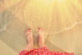 Feet girl on the sea in the water, close-up. Girl stands near the beach. Woman feet on the sand near the sea