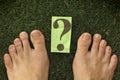 Feet on green grass which has a question mark on it Royalty Free Stock Photo