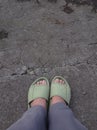 feet in a green sandals ,in aspalt road background