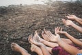 Feet and hand of children praying for the rain on cracked dry ground