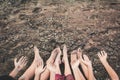 Feet and hand of children praying for the rain on cracked dry ground