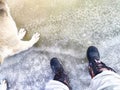 Feet of Hunter or fisherman in big warm boots And paws of dog on snow. Top view. Fisherman on ice of river, lake