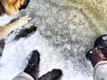 Feet of Hunter or fisherman in big warm boots And paws of dog on snow. Top view. Fisherman on ice of river, lake