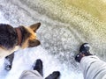 Feet of Hunter or fisherman in big warm boots And paws of dog on snow. Top view. Fisherman on ice of river, lake