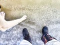 Feet of Hunter or fisherman in big warm boots And paws of dog on snow. Top view. Fisherman on ice of river, lake