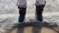 Feet of Hunter or fisherman in big warm boots on a winter day on snow. Top view. Fisherman on the ice of a river, lake