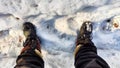 Feet of Hunter or fisherman in big warm boots on a winter day on snow. Top view. A fisherman on the ice of a river, lake