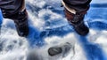 Feet of Hunter or fisherman in big warm boots on a winter day on snow. Top view. A fisherman on the ice of a river, lake