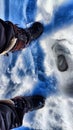 Feet of Hunter or fisherman in big warm boots on a winter day on snow. Top view. A fisherman on the ice of a river, lake