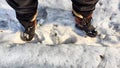 Feet of Hunter or fisherman in big warm boots on a winter day on snow. Top view. A fisherman on the ice of a river, lake