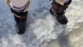 Feet of Hunter or fisherman in big warm boots on a winter day on snow. Top view. Fisherman on the ice of a river, lake