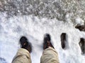 Feet of Hunter or fisherman in big warm boots on a winter day on snow. Top view. Fisherman on the ice of a river, lake