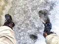 Feet of Hunter or fisherman in big warm boots on a winter day on snow. Top view. Fisherman on the ice of a river, lake