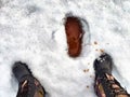 Feet of Hunter or fisherman in big warm boots on a winter day on snow. Top view. Fisherman on the ice of a river, lake