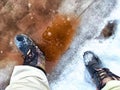 Feet of Hunter or fisherman in big warm boots on a winter day on snow. Top view. Fisherman on the ice of a river, lake