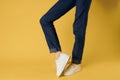 feet jeans fashion shoes white sneakers yellow background