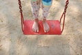 Feet of kid standing on red metal swing