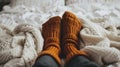 feet in knitted woollen socks peeking out from under a knitted warm blanket in winter. warm and cosy