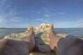 Feet and legs of a young man sunbathing on the rocks surrounded by the sea Royalty Free Stock Photo