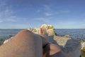 Feet and legs of a young man sunbathing on the rocks surrounded by the sea Royalty Free Stock Photo