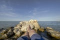 Feet and legs of a young man sunbathing on the rocks surrounded by the sea Royalty Free Stock Photo