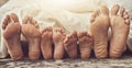 Feet, love and family in bed together to relax on a weekend morning in their home with flare. Mother, father and Royalty Free Stock Photo