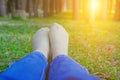 feet lying resting on grass in pine tree forest. leg wearing jeans relaxing in park Royalty Free Stock Photo