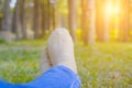 feet lying resting on grass in pine tree forest. leg wearing jeans relaxing in park Royalty Free Stock Photo