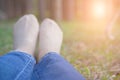 feet lying resting on grass in pine tree forest. leg wearing jeans relaxing in park Royalty Free Stock Photo