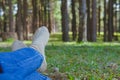 feet lying resting on grass in pine tree forest. leg wearing jeans relaxing in park Royalty Free Stock Photo