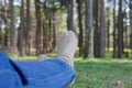 feet lying resting on grass in pine tree forest. leg wearing jeans relaxing in park Royalty Free Stock Photo