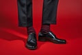 Feet of man in business pants and shoes with funny red and black striped socks Royalty Free Stock Photo