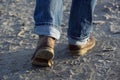 Feet of man with leather boots and rolled up jeans walking forward on the sand on a beach, leisure activity concept