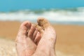 Feet of a man lying on the beach. Vacationer relaxes near the azure sea at sunny day.