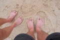 Feet of a man and woman couple standing on a sandy beach. Royalty Free Stock Photo