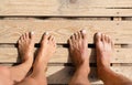 Feet of man and woman stand on the wooden pallet. Relaxation on the beach. Family vacation concept. Top view. Copy space