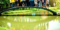 Feet of many people sit and stand to take pictures on the curved wooden bridge