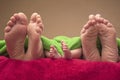 Feet of newborn baby and parents together on the bed